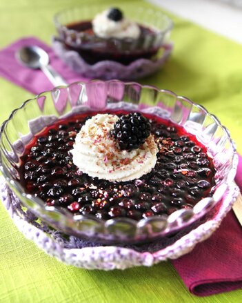 Foto von einem Schälchen mit Beeren-Gewürzgelee. Auf dem dunkelroten Gelee ist ein weißes Obers Tüpfelchen und eine Brombeere zu sehen. | © SONNENTOR