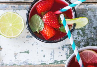 Auf dem Foto sind zwei Tassen mit roter Erdbeer Limonade zu sehen. Darin sind Erdbeeerstücke und Limettenscheiben zu sehen. | © SONNENTOR