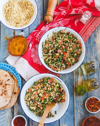 Auf dem Foto sind zwei Schüsseln mit Bulgur zu sehen. Daneben sind Öle, Fladenbrot und zahlreiche Gewürze zu sehen. | © SONNENTOR