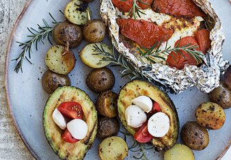 Auf dem Foto sieht man einen Teller mit allerlei vegetarischem Grillgut. Beispielsweise sieht man Kartoffelspieße, Avocados und ein Tomaten-Feta Päckchen. | © SONNENTOR