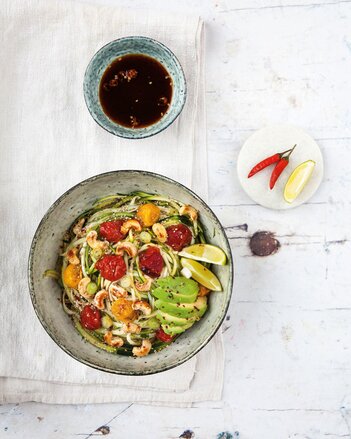 Auf dem Foto ist eine Bowl Asiatische Zucchini-Nudeln zu sehen, garniert mit Früchten, Gemüse und Nüssen. | © SONNENTOR