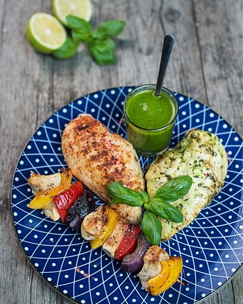 Auf dem Foto sind zwei Hühnerbrustfilets und ein Hühnerspieß zu sehen. Daneben steht ein Gläschen mit Salsa Verde. | © SONNENTOR