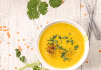 Auf dem Foto sieht man zwei Teller Linsen-Currysuppe. Dahinter ist ein Topf mit Linsen zu sehen. | © SONNENTOR