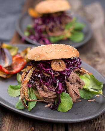 Auf dem Foto ist ein Pulled Beef Burger zu sehen. Im Burger ist auch Vogerlsalat und Kohl zu sehen. | © SONNENTOR