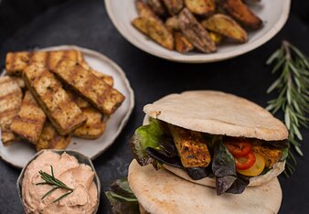 Auf dem Foto sieht man zwei Pita Brote mit Veggie Gyros. Im Hintergrund sieht man einen Teller mit Veggie Gyros und eine Schale mit Kartoffelwedges. | © SONNENTOR