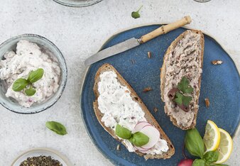 Auf dem Foto sind der Frischkäse-Basilikum und der Rosmarin-Bohnen Aufstriche zu sehen. Daneben sind zwei Scheiben Brot mit den Aufstrichen darauf zu sehen. | © SONNENTOR