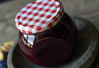 Auf dem Foto sieht man ein Glas mit Zimt-Marmelade. Daneben liegen Zwetschken und Zimtstangen. | © SONNENTOR