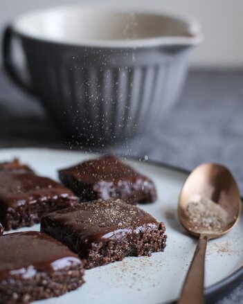 Auf dem Foto sind Brownie Chai Bites auf einem Teller zu sehen. Die Brownies werden gerade mit Chai bestäubt. | © SONNENTOR