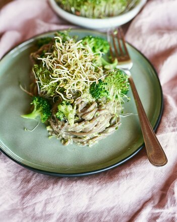 Auf dem Foto ist ein grüner Teller mit Pasta mit Sprossenpesto zu sehen. Auf er Pasta sind Sprossen und Brokkoli zu sehen. | © SONNENTOR