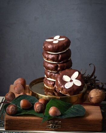 Auf dem Foto ist ein goldenes Service mit mehreren Elisenlebkuchen zu sehen. Daneben sind verschiedene Nüsse zu sehen. | © SONNENTOR