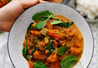 Auf dem Foto sieht man einen Teller mit Süßkartoffelcurry mit Spinat. Man sieht wie jemand den Teller hält. | © SONNENTOR