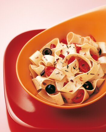 Auf dem Foto ist ein orangenes Schälchen mit Scharfmacher-Pasta zu sehen. In der Pasta sind auch Oliven und Tomaten zu sehen. | © SONNENTOR