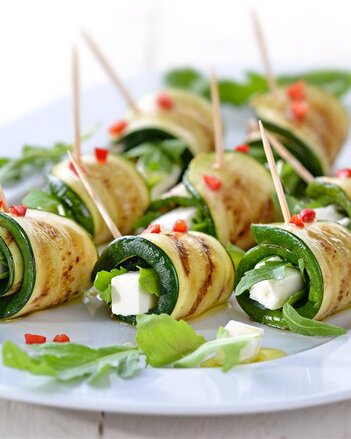 Auf dem Foto sind Schafkäse Zucchiniröllchen zu sehen. Darauf verteilt liegt Rucola. | © SONNENTOR