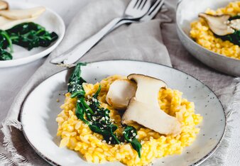 Auf dem Foto ist ein Teller mit Kürbisrisotto zu sehen. Das Risotto ist mit Steinpilzen und Blattspinat angerichtet. | © SONNENTOR