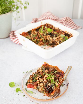 Auf dem Foto sieht man einen transparenten Teller mit einem Stück Champignon-Steinpilz-Lasagne darauf. | © SONNENTOR