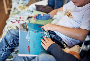 Auf dem Foto ist ein Junge beim Buch Anschauen zu sehen. | © SONNENTOR