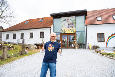 Auf dem Foto befindet sich Hannes im Jahr 2023 mit dem 35-jahre Jubiläums T-Shirt vorm Haupteingang am Standort Sprögnitz. | © SONNENTOR