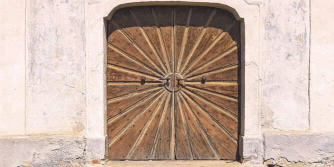 Das Bild zeigt ein Original des Sonnentors aus Holz mit den typischen Strahlen in den Torflügeln und dem Sonnenkreis in der Mitte.  | © SONNENTOR