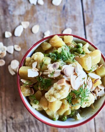 Auf dem Foto ist eine Schüssel mit dem Erdäpfel-Curry zu sehen. Darüber gestreut sind Mandelblättchen. | © SONNENTOR