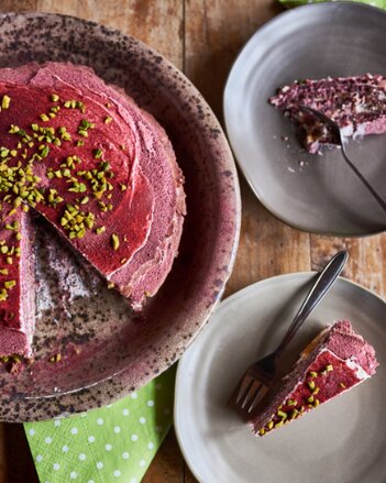 Auf dem Foto ist eine Rote-Rüben Mohntorte zu sehen. Daneben sind zwei Teller mit kleinen Stücken Mohntorte zu sehen. | © SONNENTOR