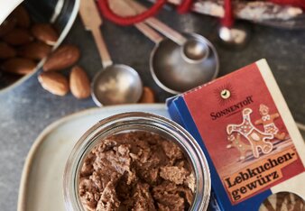 Auf dem Foto ist ein Glas mit Lebkuchen-Mandelbutter zu sehen. Daneben sieht man eine Packung Lebkuchengewürz und Mandeln. | © SONNENTOR