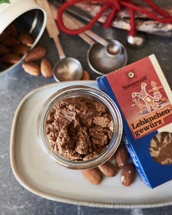 Auf dem Foto ist ein Glas mit Lebkuchen-Mandelbutter zu sehen. Daneben sieht man eine Packung Lebkuchengewürz und Mandeln. | © SONNENTOR