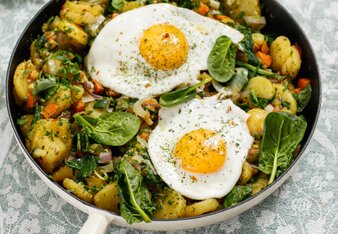 Auf dem Foto sieht man eine Pfanne mit Veggie Gröstl. Darauf sind zwei Spiegeleier und Babyspinat zu sehen. | © SONNENTOR