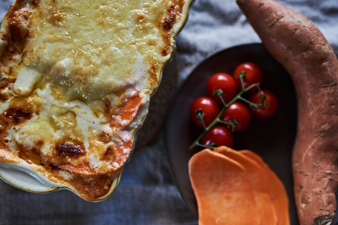 Auf dem Foto ist glutenfrei Lasagne aus Süßkartoffeln zu sehen. Daneben sieht man Tomaten und Süßkartoffelscheiben. | © SONNENTOR