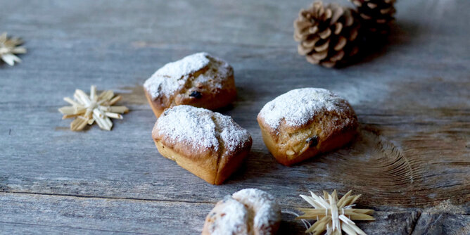 Auf dem Foto sind Mini-Gewürzstollen zu sehen. Daneben liegen auch kleine Holzsterne und Zapfen. | © SONNENTOR